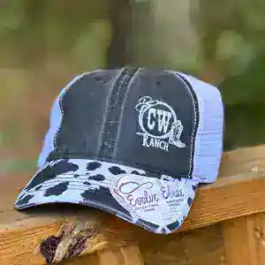 A distressed CW Ranch trucker cap with an embroidered logo and a cow print brim
